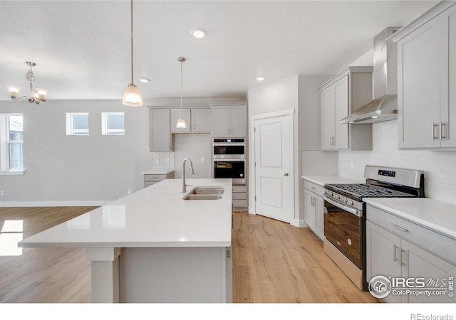 1815 Chaffee Crest Dr, Berthoud, CO 80513 - kitchen featuring stainless steel appliances, sink, wall chimney range hood, a center island with sink, and hanging light fixtures