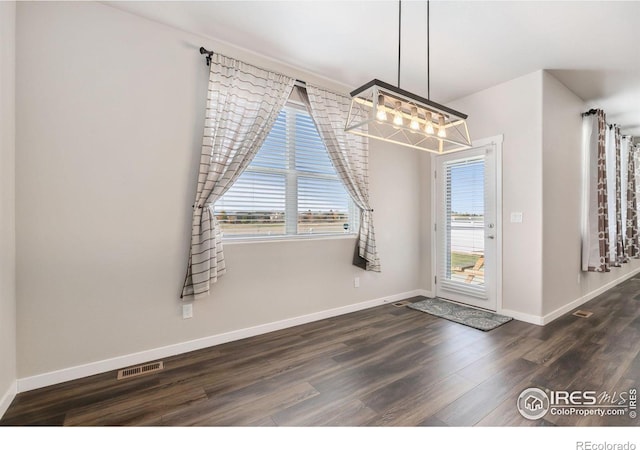 unfurnished dining area with dark wood-type flooring