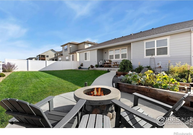 rear view of property featuring a fire pit, a yard, a patio area, and fence