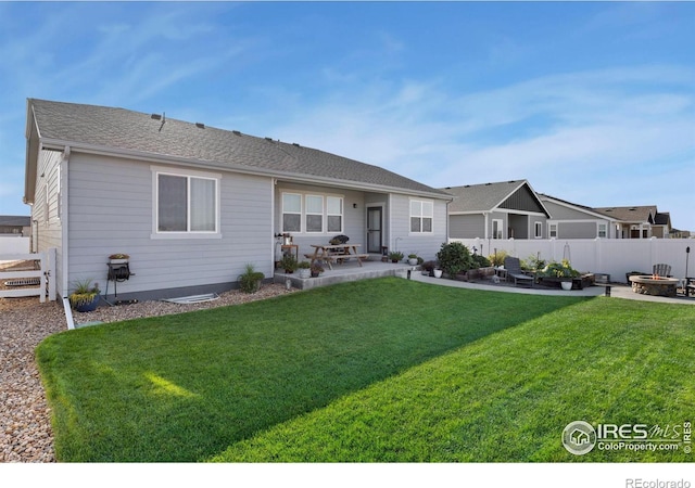 rear view of property featuring a yard, an outdoor fire pit, a patio, and fence