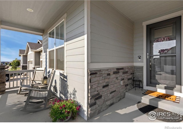 doorway to property featuring stone siding and a porch