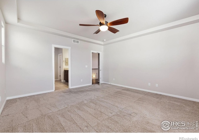 unfurnished bedroom with a tray ceiling, baseboards, visible vents, and carpet flooring