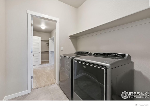 clothes washing area with light tile patterned floors, light colored carpet, laundry area, independent washer and dryer, and baseboards