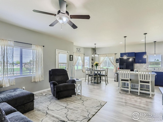 living room with ceiling fan, light wood-type flooring, and sink