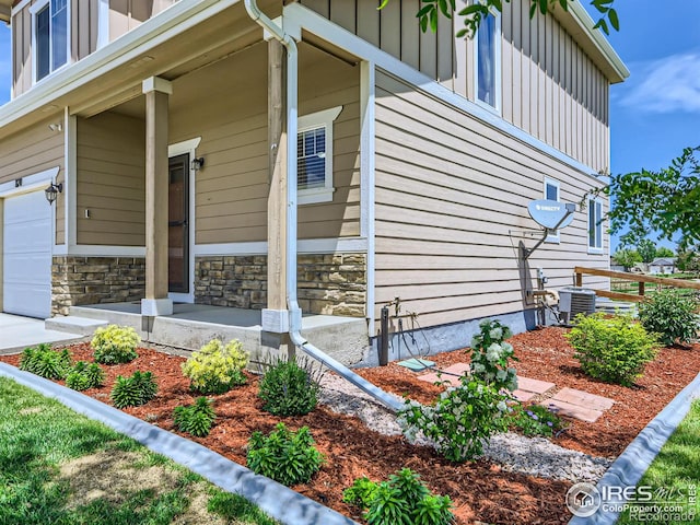 view of property exterior featuring central air condition unit, covered porch, and a garage