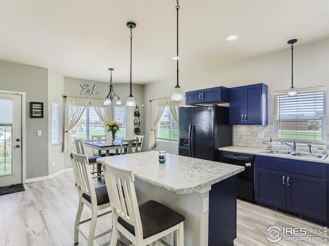 kitchen with sink, a kitchen island, a healthy amount of sunlight, and black appliances