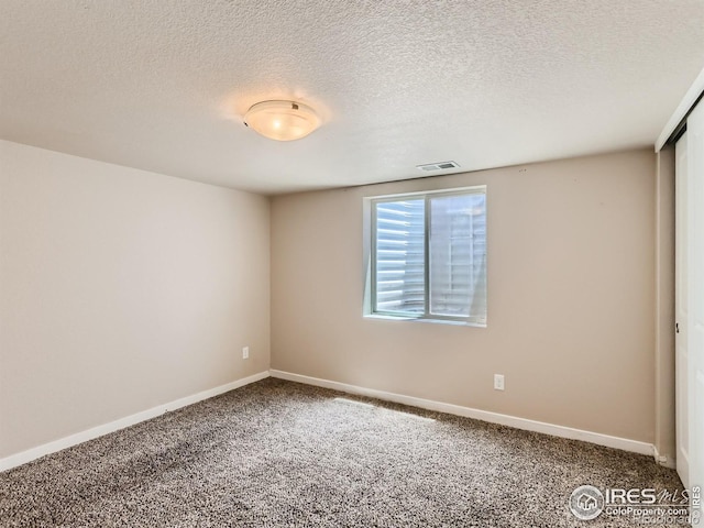 empty room with carpet and a textured ceiling