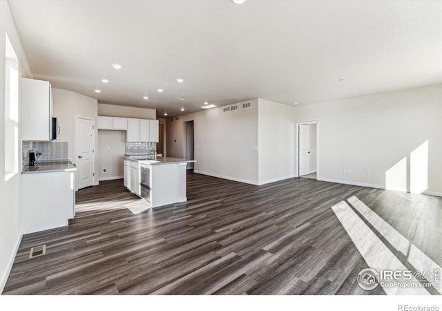 kitchen with sink, white cabinets, tasteful backsplash, dark hardwood / wood-style floors, and a center island with sink