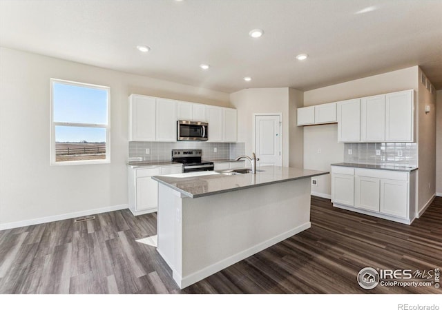 kitchen featuring sink, white cabinets, stainless steel appliances, and an island with sink