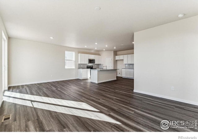 unfurnished living room featuring sink and dark hardwood / wood-style floors