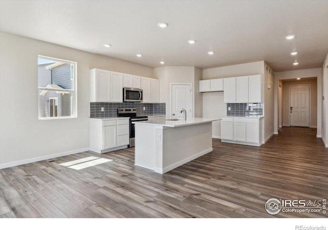 909 Harvard St, Johnstown, CO 80534 - kitchen featuring tasteful backsplash, stainless steel appliances, wood finished floors, and white cabinets