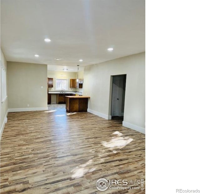 unfurnished living room featuring hardwood / wood-style flooring and sink