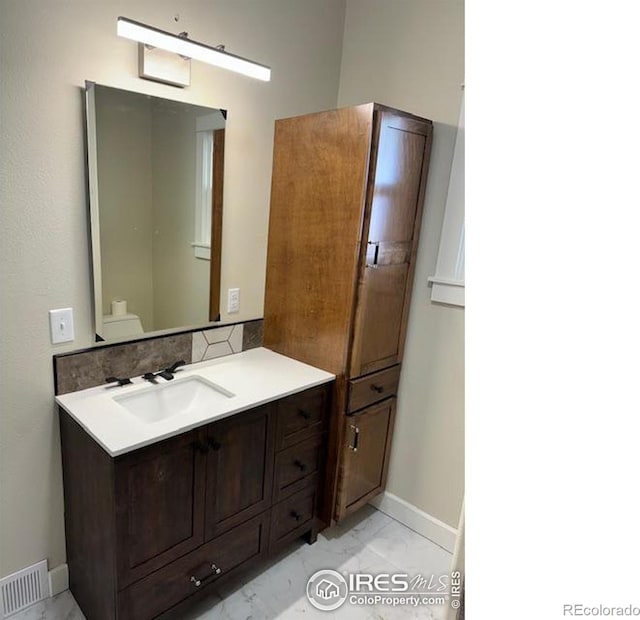 bathroom with decorative backsplash, vanity, and toilet