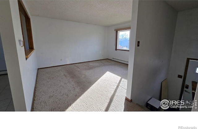 empty room with a textured ceiling, light colored carpet, and baseboard heating