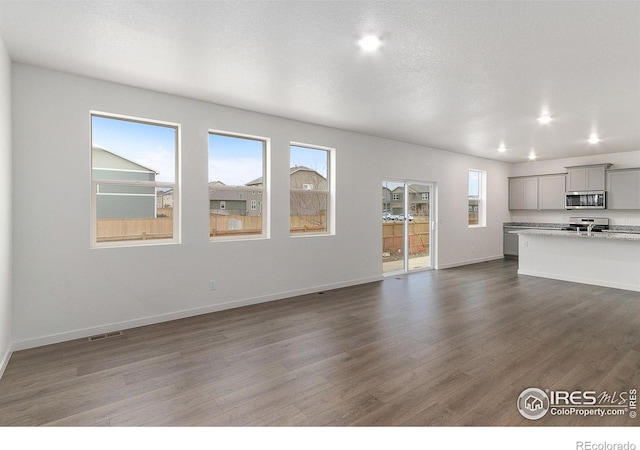 unfurnished living room featuring dark hardwood / wood-style flooring and a textured ceiling