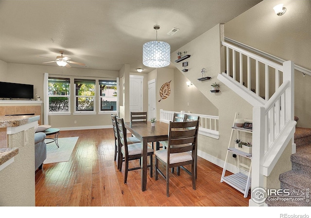 dining area featuring wood-type flooring and ceiling fan with notable chandelier