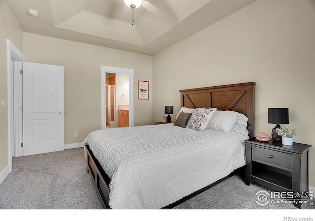 carpeted bedroom with ceiling fan, a raised ceiling, and connected bathroom