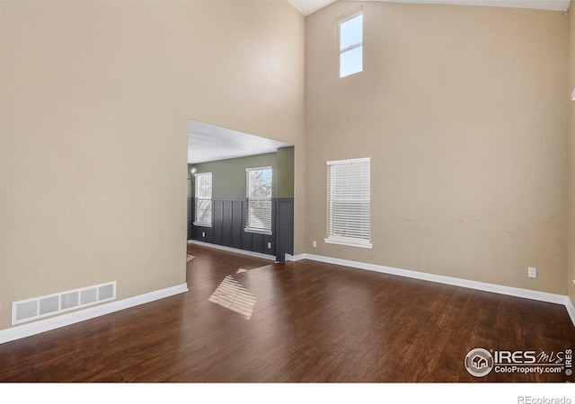 interior space featuring a high ceiling, dark hardwood / wood-style floors, and a wealth of natural light