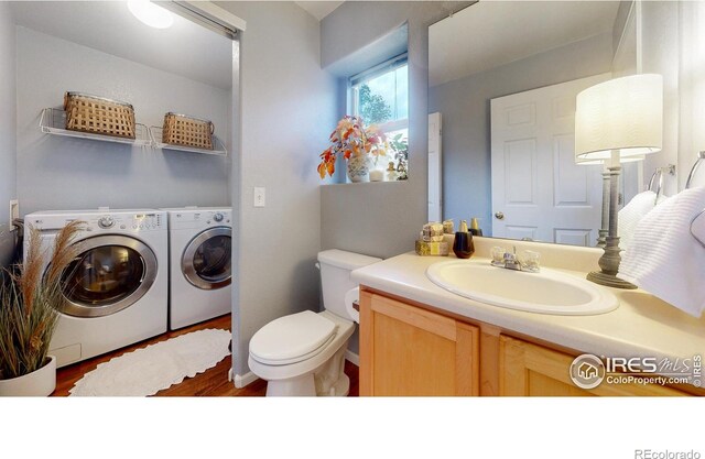 bathroom featuring washing machine and clothes dryer, vanity, wood-type flooring, and toilet