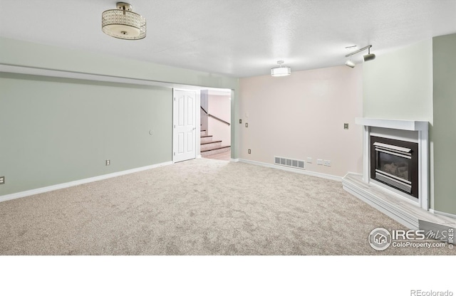 unfurnished living room featuring a textured ceiling and light carpet