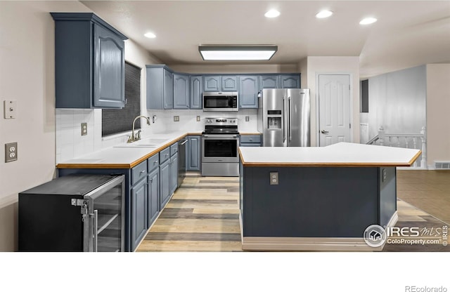 kitchen featuring appliances with stainless steel finishes, tasteful backsplash, sink, light hardwood / wood-style flooring, and a kitchen island