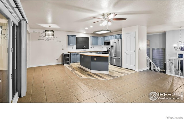 kitchen featuring appliances with stainless steel finishes, beverage cooler, sink, a center island, and hanging light fixtures