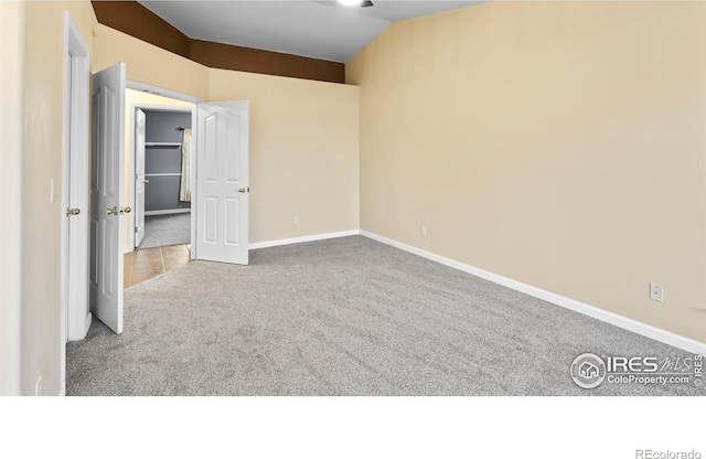 unfurnished bedroom featuring light colored carpet and vaulted ceiling