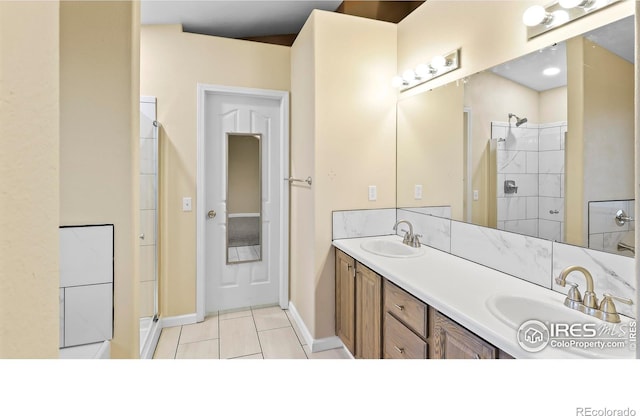 bathroom featuring tile patterned flooring, vanity, and tiled shower