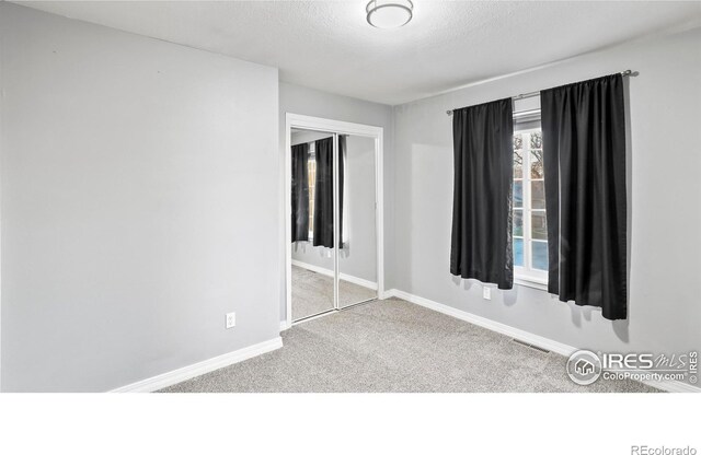 spare room with light carpet and a textured ceiling