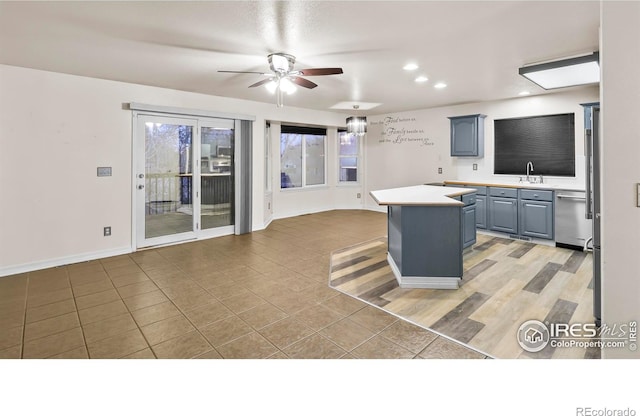 kitchen with ceiling fan, a center island, sink, light hardwood / wood-style flooring, and stainless steel dishwasher