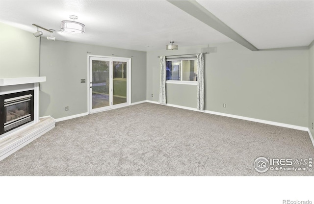 unfurnished living room with beamed ceiling and carpet floors