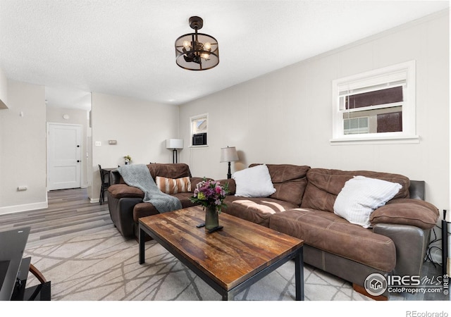 living room with a textured ceiling, light hardwood / wood-style floors, and an inviting chandelier