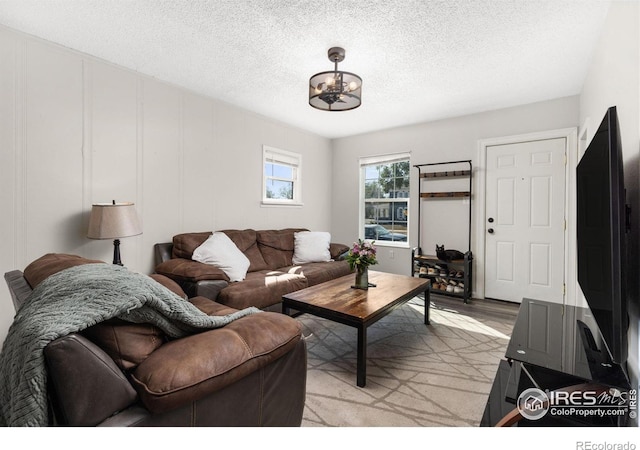 living room with a notable chandelier, a textured ceiling, and light hardwood / wood-style flooring