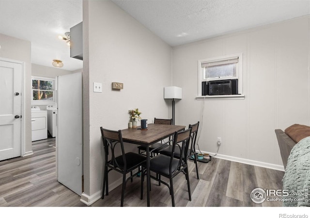 dining space featuring hardwood / wood-style floors, a textured ceiling, cooling unit, and washing machine and clothes dryer