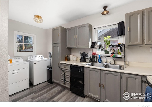 kitchen featuring gray cabinetry, dark wood-type flooring, sink, washing machine and dryer, and black dishwasher