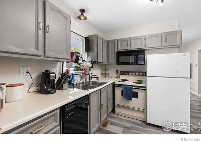 kitchen with sink, light hardwood / wood-style floors, gray cabinetry, and black appliances