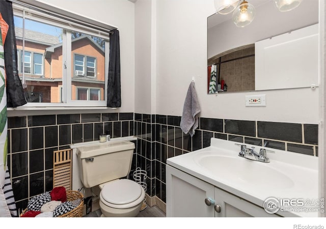 bathroom with vanity, tile walls, and toilet