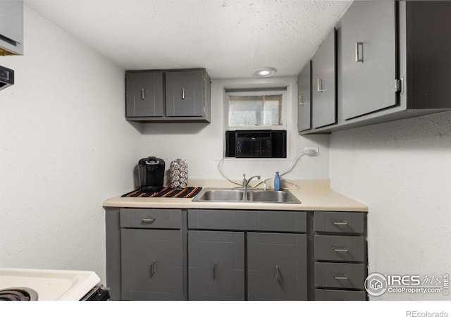 kitchen with gray cabinetry, a textured ceiling, cooling unit, sink, and range