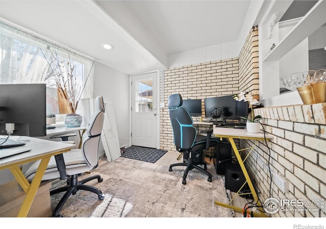 carpeted office space featuring brick wall