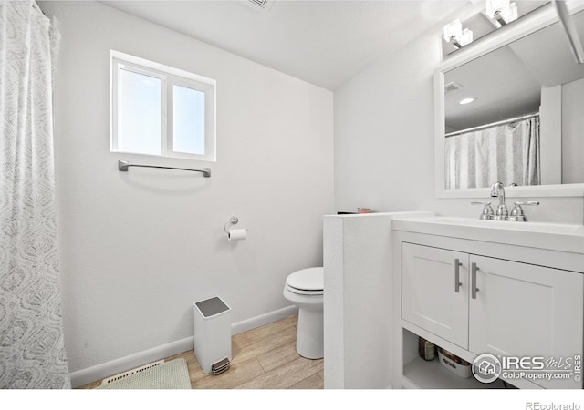 bathroom with hardwood / wood-style floors, vanity, and toilet