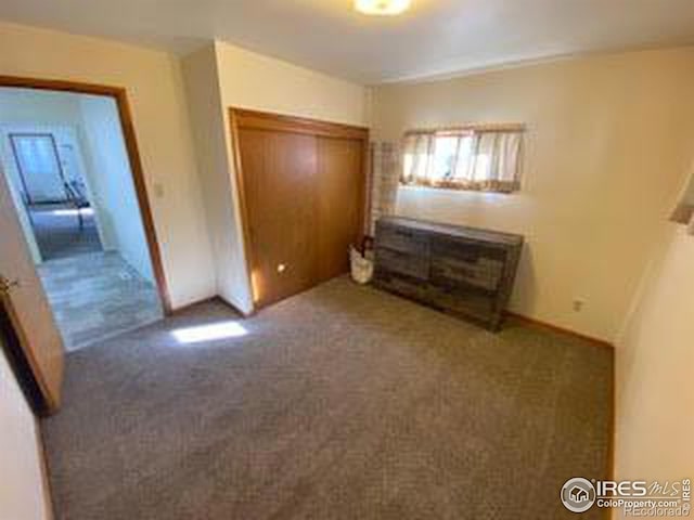 unfurnished bedroom with a closet and dark colored carpet