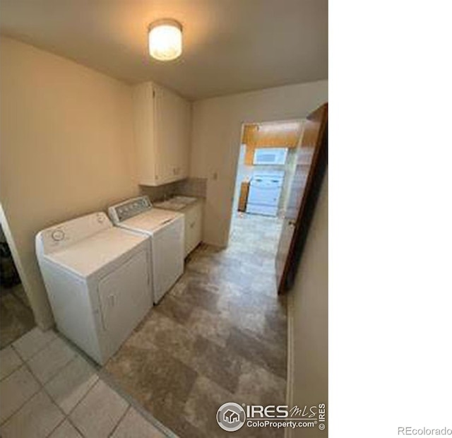 clothes washing area with washer and clothes dryer and cabinets