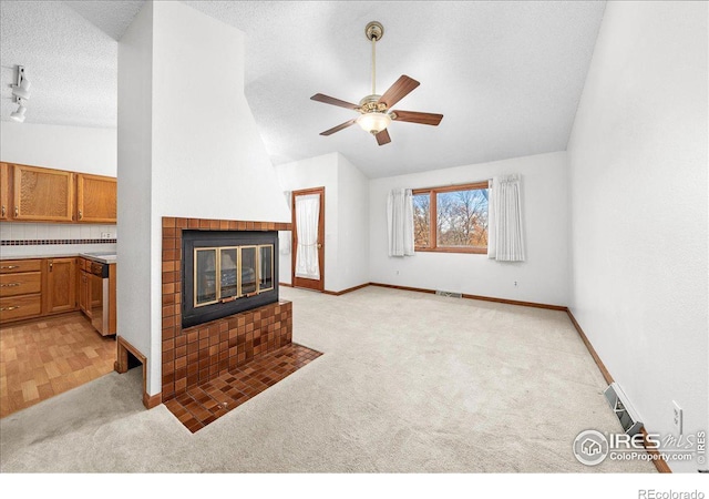 living area featuring a fireplace, lofted ceiling, a ceiling fan, light carpet, and a textured ceiling