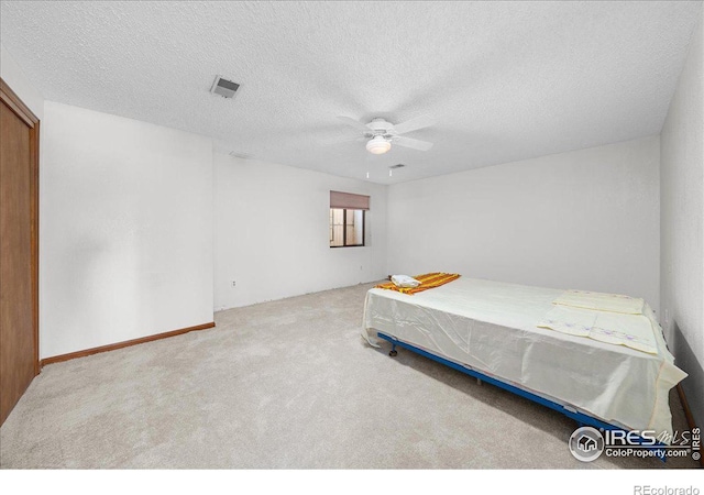 bedroom with a ceiling fan, visible vents, a textured ceiling, and light colored carpet