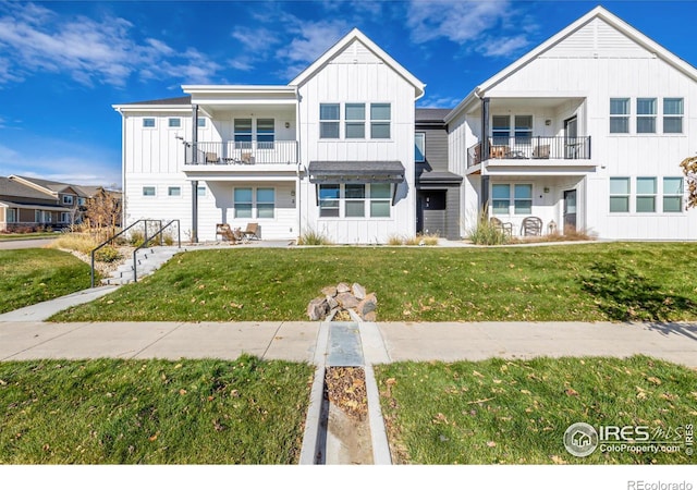 view of property with a balcony and a front yard