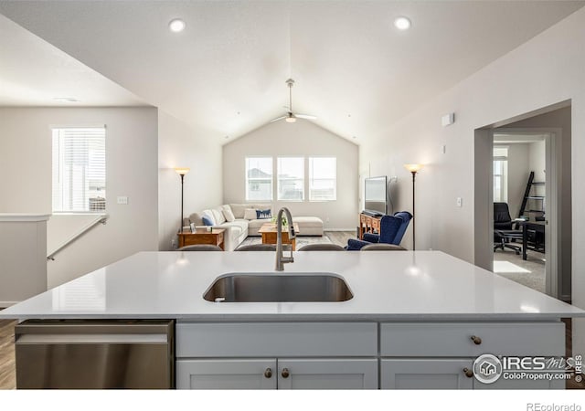 kitchen with ceiling fan, sink, stainless steel dishwasher, an island with sink, and vaulted ceiling