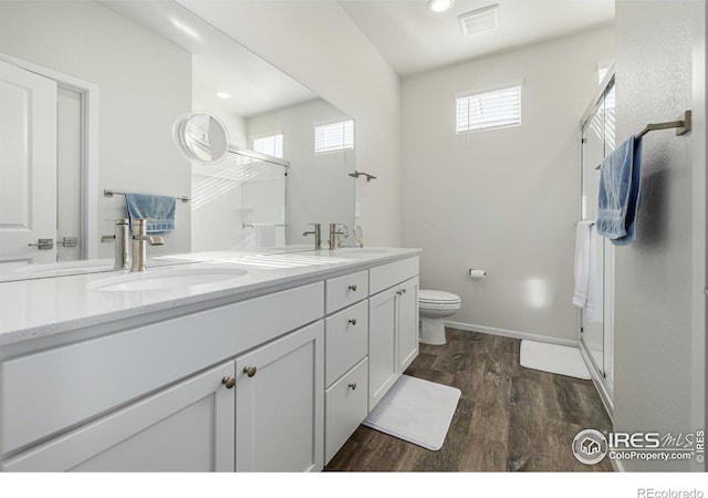 bathroom featuring vanity, toilet, wood-type flooring, and a shower with door