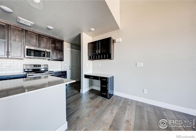 kitchen featuring decorative backsplash, light wood-type flooring, dark brown cabinetry, stainless steel appliances, and a textured ceiling