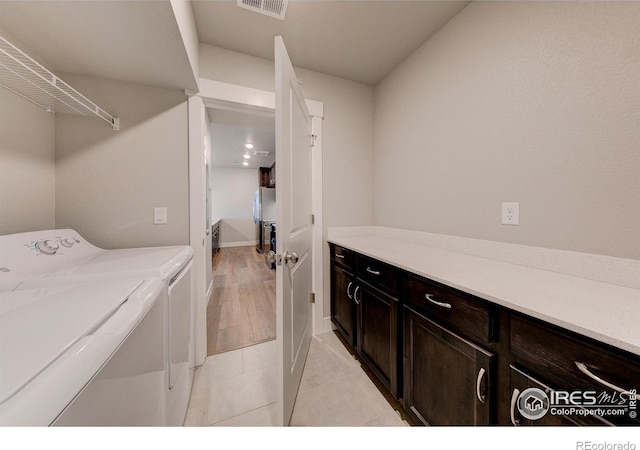 laundry room with cabinets, light wood-type flooring, and washing machine and clothes dryer