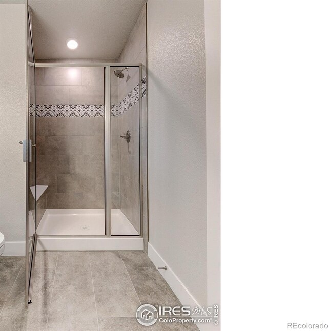 bathroom featuring tile patterned floors, toilet, and a shower with shower door